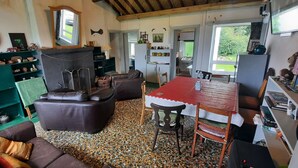 A cozy living room with a red table, a green bookshelf, and a pebbled floor. - Unique beachfront cottage at Fintra Bay Donegal (Killybegs)