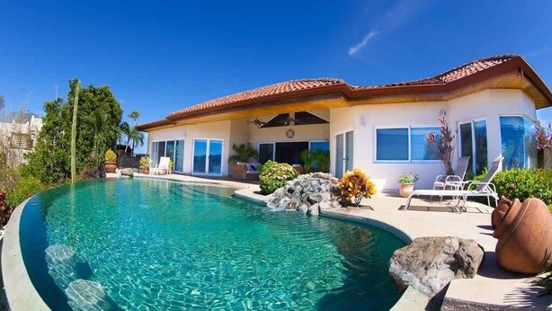 A house with a swimming pool, a patio with lounge chairs, and a garden with rocks and plants. - Luxury Villa | Infinity Pool & Ocean Views (Playa Potrero)