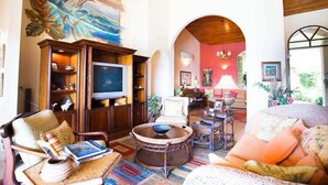 A spacious living room with a television, comfortable seating, and a vibrant mural. - Luxury Villa | Infinity Pool & Ocean Views (Playa Potrero)
