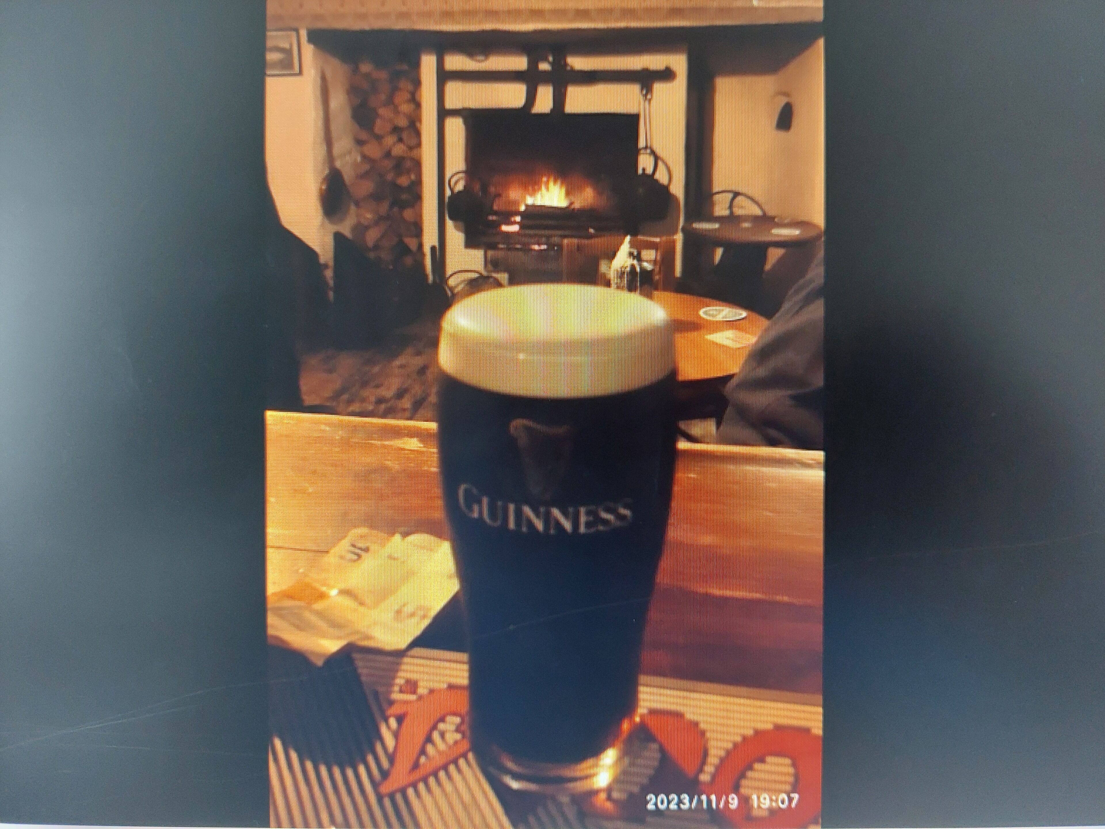 A glass of Guinness beer on a table with a fireplace in the background.