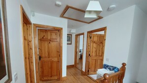 Ein Flur mit Holztüren, einem Holzstuhl und einer weißen Deckenleuchte.