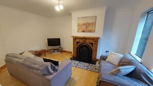 Ein Wohnzimmer mit zwei Sofas, einem Fernseher, einem Kamin und einem Gemälde an der Wand.