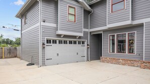 A two-story house with a garage, a small window, and a brick foundation. - Luxury Apartment | Pvt. Parking | @ Kyle Field (College Station)