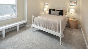 A bedroom with a bed, two bedside tables, a bench, and a window. - Luxury Apartment | Pvt. Parking | @ Kyle Field (College Station)