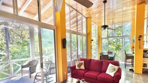 A spacious room with a red sofa, a coffee table, and a balcony with wicker furniture. - Casa Amable by Ronny's place - Manuel Antonio (Quepos)