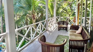 A covered outdoor seating area with wooden furniture and a view of lush greenery. - Casa Amable by Ronny's place - Manuel Antonio (Quepos)