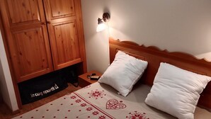 Un dormitorio con cama, armario de madera y una lámpara de pared.