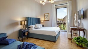 Une chambre d’hôtel avec un lit, des tables de chevet, une télévision, un balcon avec vue et une plante en pot.
