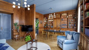 Un salon spacieux doté d’un plancher en bois, d’un canapé bleu, d’une table à manger avec des chaises et d’une bibliothèque remplie de livres.