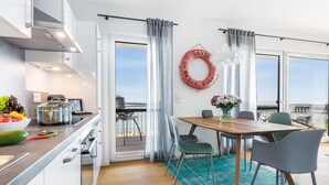 A modern kitchen with a view of the sea, a dining area with a wooden table and chairs, and a life ring on the wall. - Beautiful apartment in Olpenitz (Olpenitz)