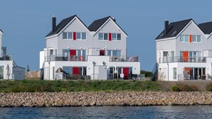 Une rangée de maisons modernes à deux étages, dotées de balcons, située au bord d’une côte rocheuse.