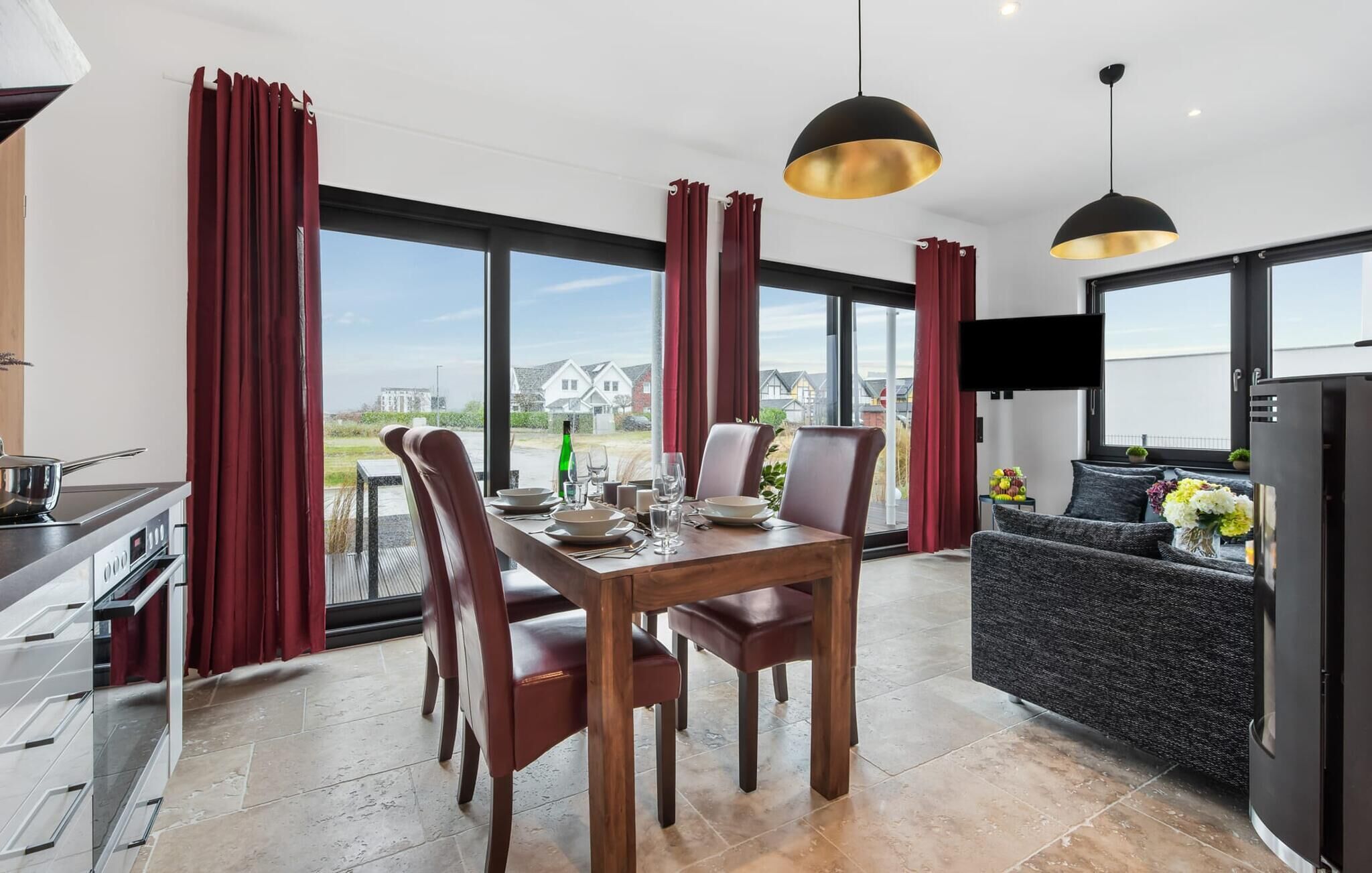 Una cocina moderna con comedor, ventanas grandes y vistas a casas.
