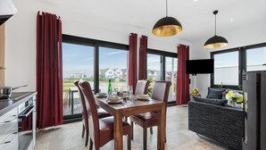 Une cuisine moderne avec un coin repas, de grandes fenêtres et une vue sur les maisons.
