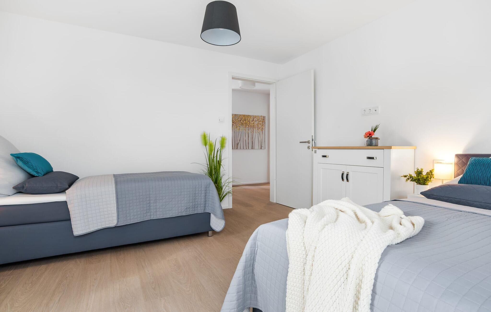 Un dormitorio moderno con una cama, un sofá, un armario y una mesita de noche con una lámpara.
