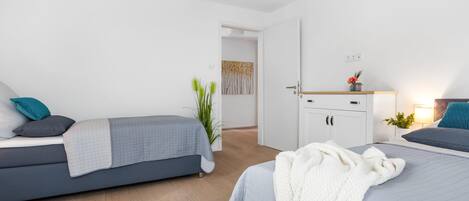 Un dormitorio moderno con una cama, un sofá, un armario y una mesita de noche con una lámpara.
