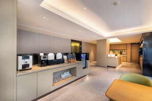 A modern hotel room with a kitchenette, a seating area, and a view of the city. - JI Hotel (Nanjing Xinjiekou Central Mall) (Nanjing)