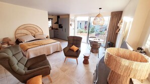 A spacious bedroom with a large bed, a sofa, and a dining area with a table and chairs. - Cocon du Clos - PEAULE (PEAULE)