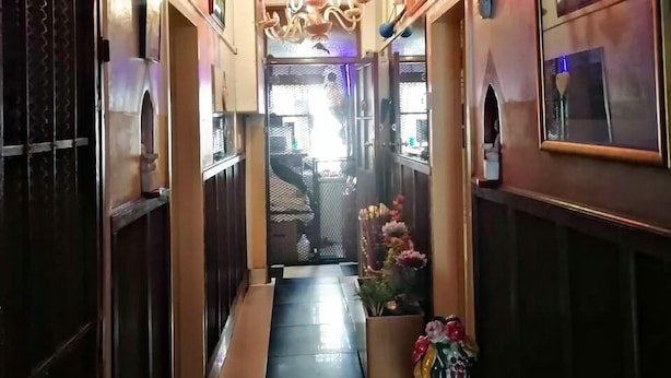 Un pasillo con un reloj y un letrero que dice 'Relax', que conduce a una habitación con una araña y vistas al exterior.