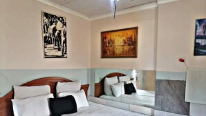 Habitación de hotel con una cama grande, cabecera, espejo y obras de arte en las paredes.