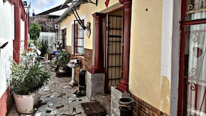 Un estrecho callejón con suelo de baldosas, plantas en macetas y un letrero de recepción.