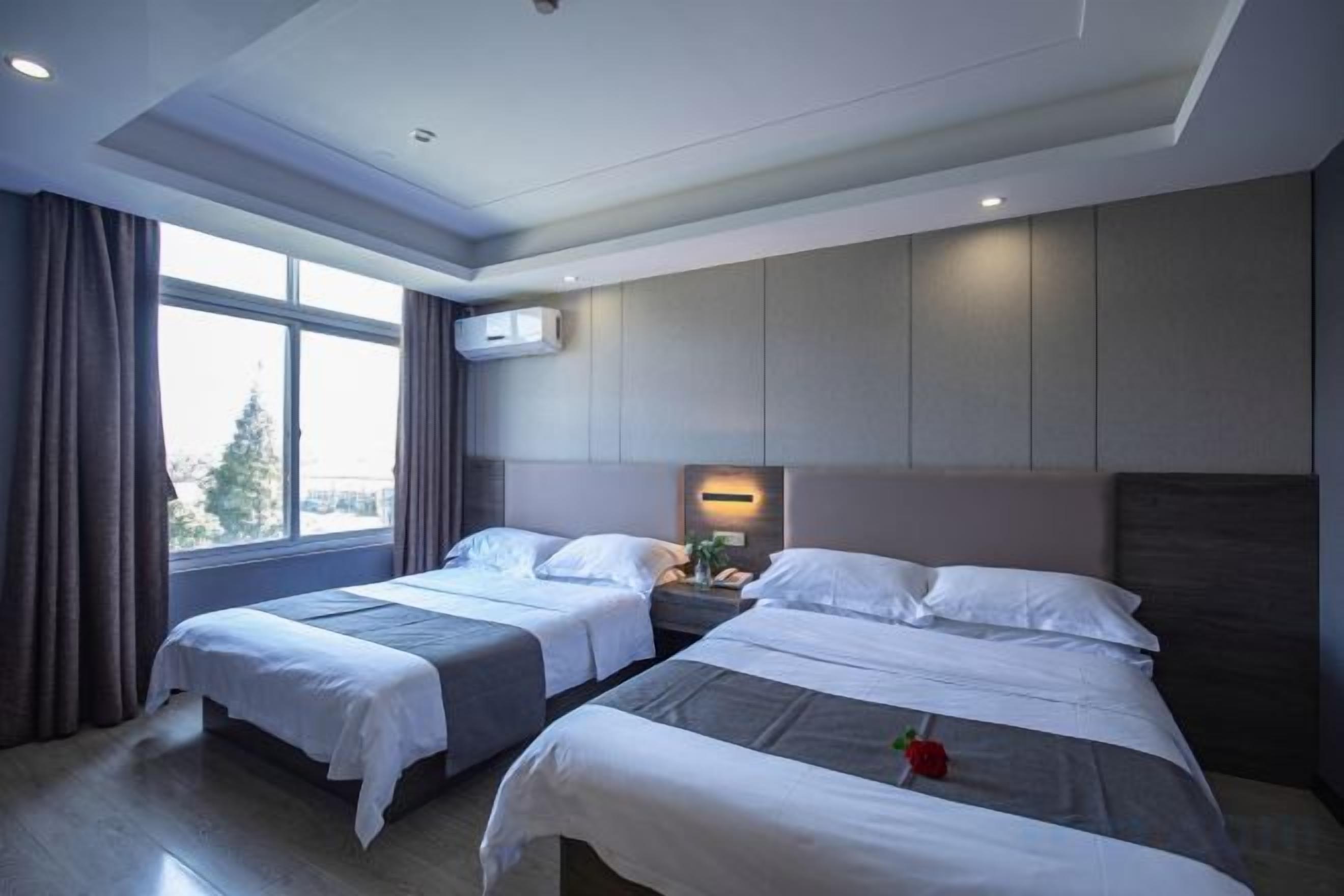 A hotel room with two beds, a large window, and a view of the city.