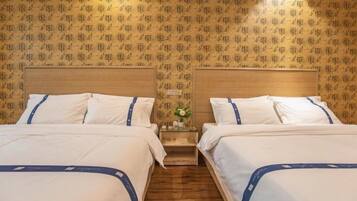 Een hotelkamer met twee bedden, houten hoofdborden en behang met een patroon.
