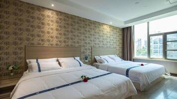 Een hotelkamer met twee bedden, een groot raam en behang met een patroon.