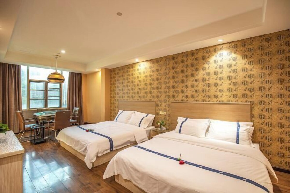 A hotel room with two beds, a desk, and a chair.