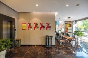 Vestíbulo de hotel con piso de mármol, mostrador de recepción, zona de estar y una pared con carteles.