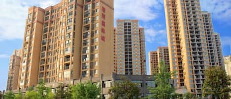 A high-rise residential building with multiple floors, balconies, and a clear sky.