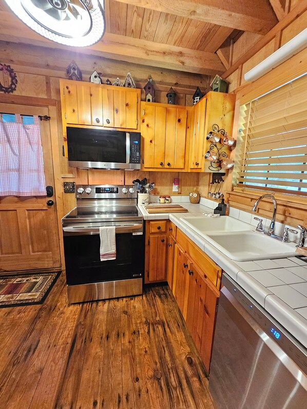 A kitchen with wooden cabinets, stainless steel appliances, and a window with blinds. - Life is a HOOT in the mountains of Suches (Suches)