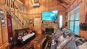 A wooden interior with a staircase, a fireplace, a television, and a sofa. - Life is a HOOT in the mountains of Suches (Suches)