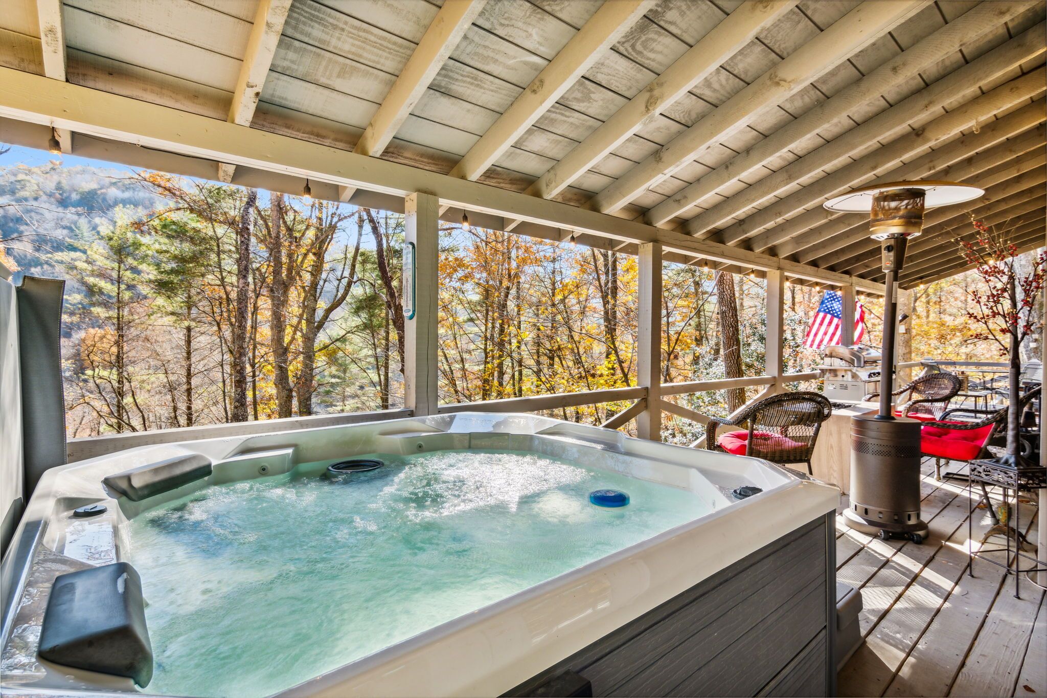 Un jacuzzi en una terraza de madera con una bandera estadounidense y sillas.