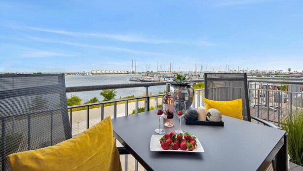 A balcony with a table set for two, overlooking a marina with boats.