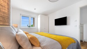 A modern bedroom with a bed, a window, a TV, and a wardrobe.