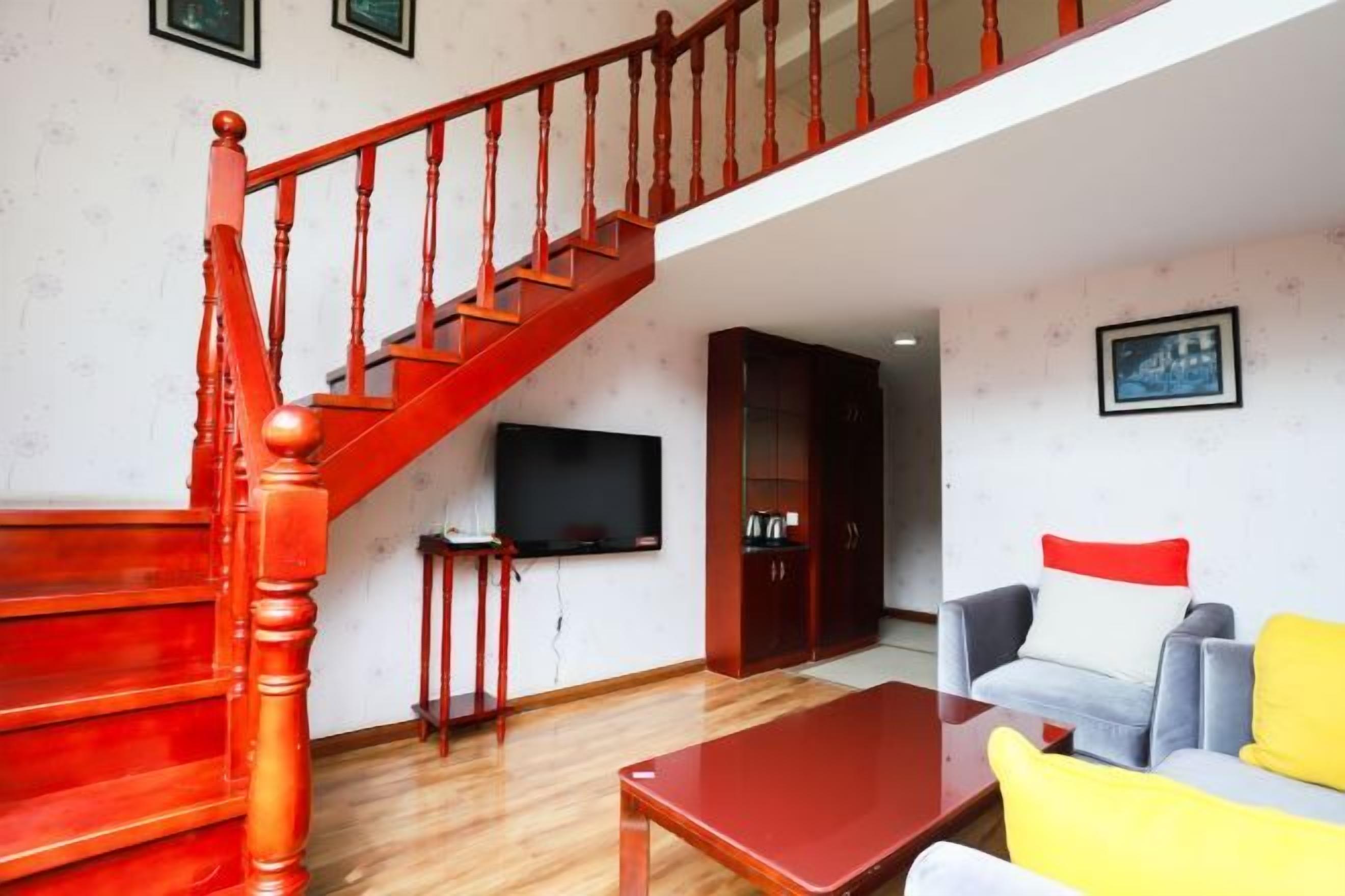 A living room with a wooden staircase, a flat-screen TV, a sofa, and a coffee table.
