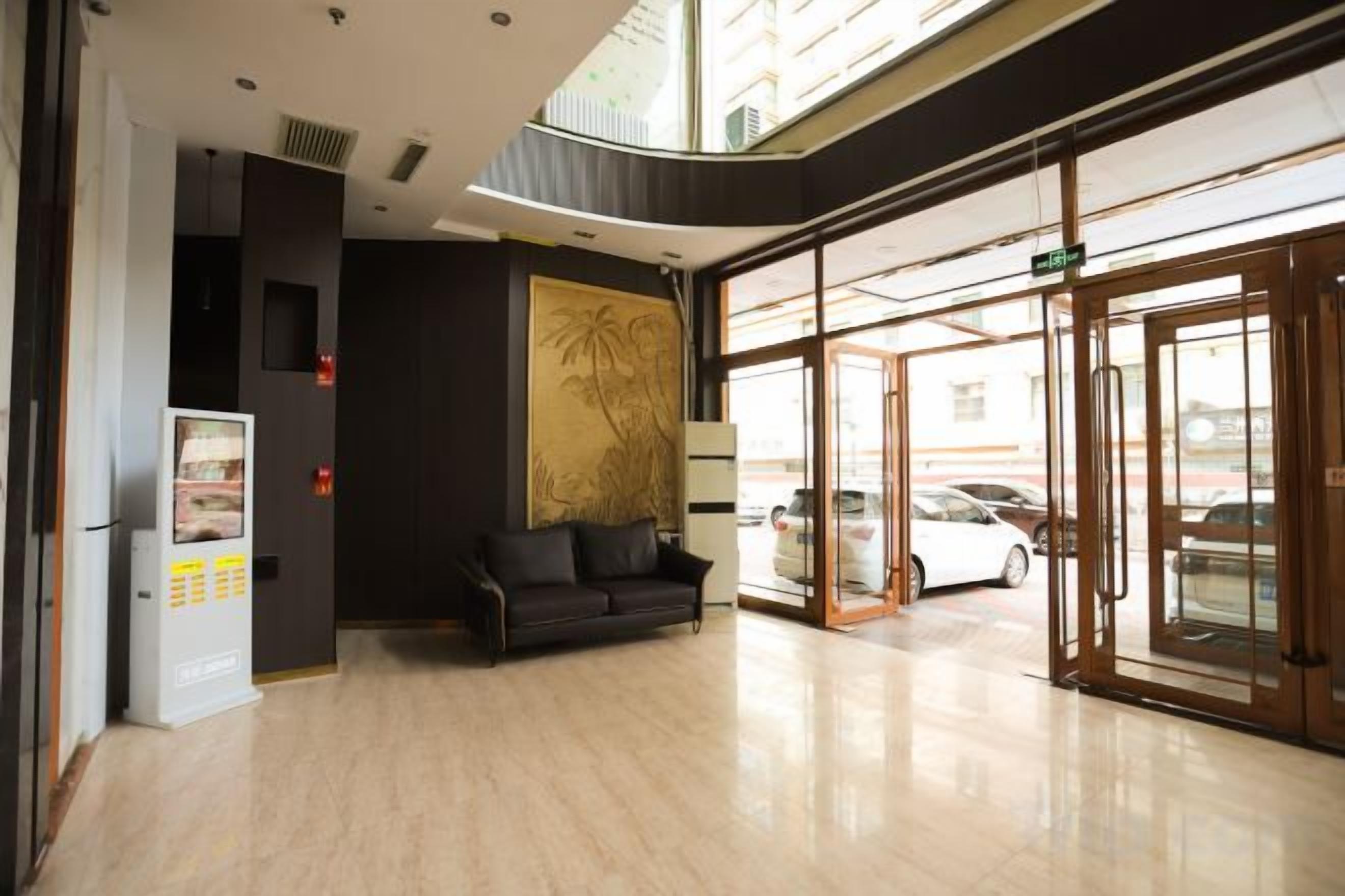 A hotel lobby with a reception desk, a sofa, a vending machine, and a glass door entrance.