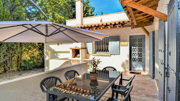 An outdoor patio with a table and chairs, a pergola, and a view of the surrounding trees. - Stunning home in Fournès (Fournès)
