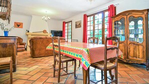 A dining area with a table set for four, surrounded by wooden chairs. A large wooden cabinet with glass doors is to the right, and a fireplace is in the background. - Stunning home in Fournès (Fournès)