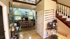 A spacious living room with a wooden staircase, a fireplace, and a view of the outdoors.