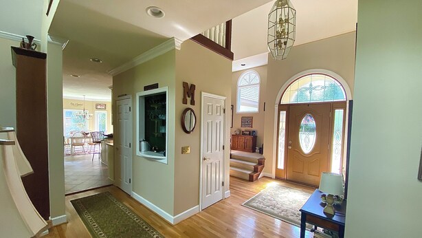 A spacious hallway with wooden flooring, a large mirror, and a chandelier.