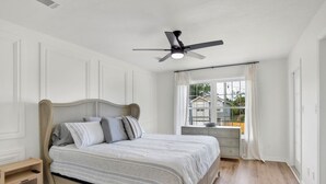 Une chambre à coucher avec un lit, une table de chevet et un ventilateur de plafond.