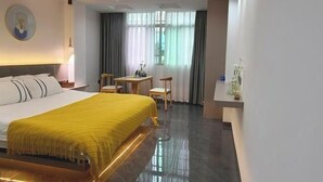 A hotel room with a bed, a desk, a chair, a small table, and a window with curtains. - YunShuiYao Tian'e Hotel (Nanjing County)
