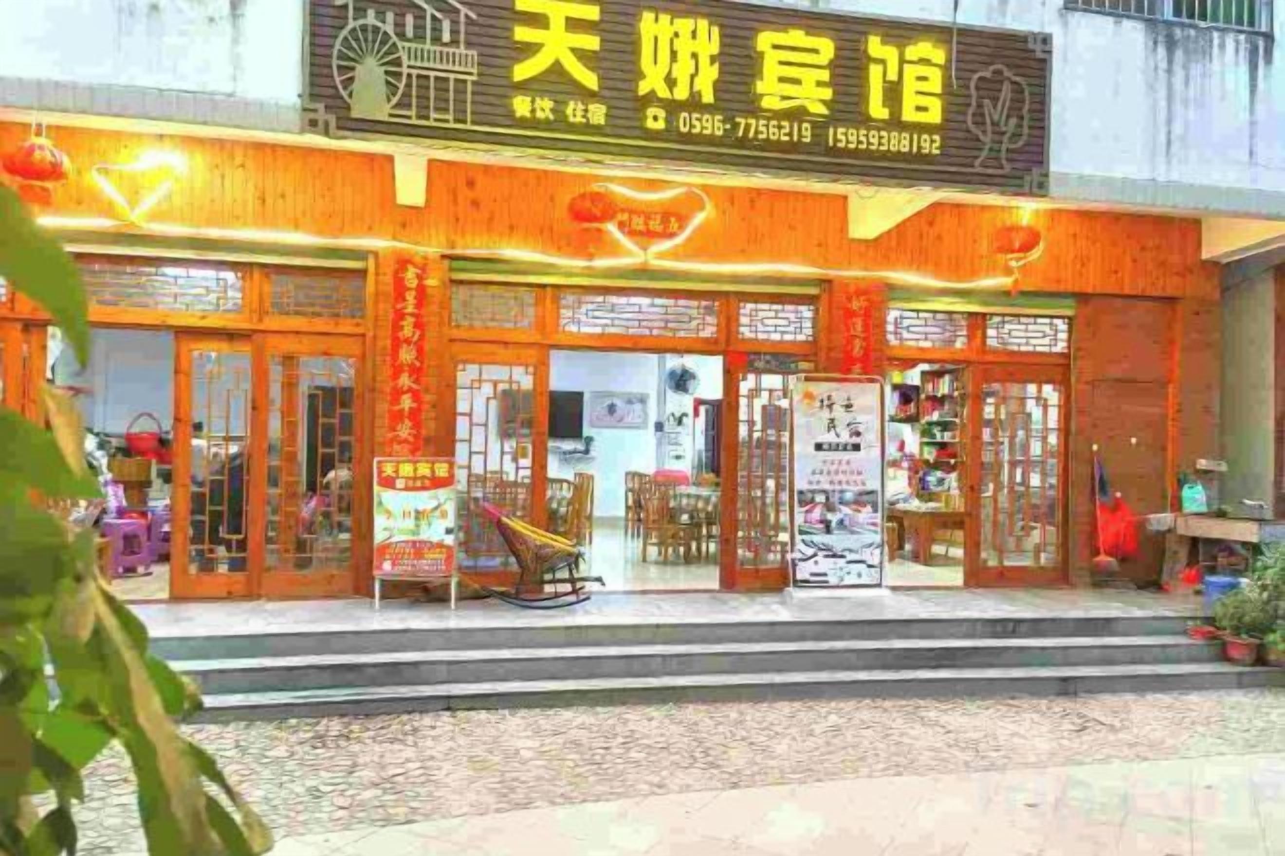 A traditional Chinese restaurant with a signboard, wooden exterior, and a seating area with tables and chairs.