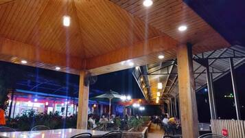 Un espacio comedor al aire libre con techo de madera y mesas.