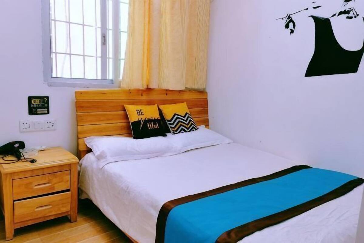 Ein Schlafzimmer mit einem hölzernen Bett, einem Nachttisch, einem Fenster mit Vorhängen und einer Wanddekoration.