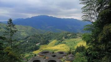 Paisagem montanhosa com campos em terraços e edifícios tradicionais de telhado arredondado.