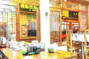 Un escaparate con un cartel en un idioma extranjero, una vitrina con varios artículos y un vehículo rojo en el exterior.