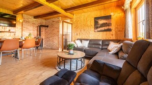Una sala acogedora con techo de madera, chimenea, sofá y comedor con sillas.
