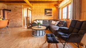 Una sala de estar acogedora con techo de madera, pared de ladrillo y un ventanal grande.